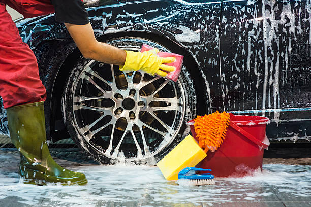 Male worker at car wash service washing a car.